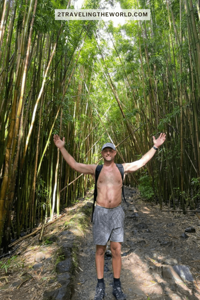 Pipiwai Trail Hike through Bamboo forest to Waimoku Falls. Man standing with his hands up with bamboo forest behind him