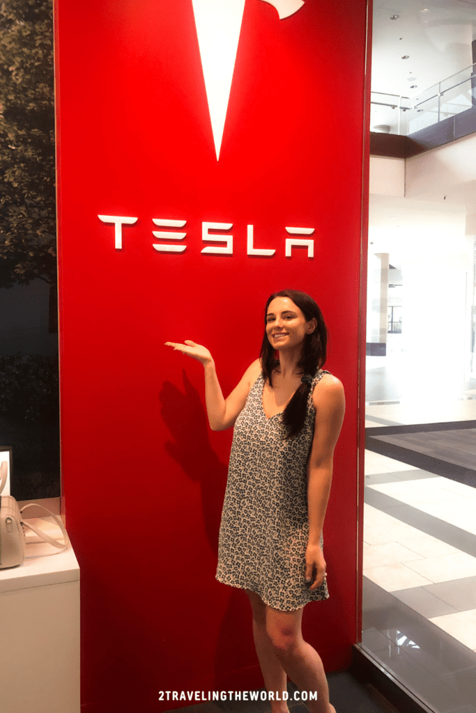 girl shopping for her tesla model y and pointing to a tesla sign
