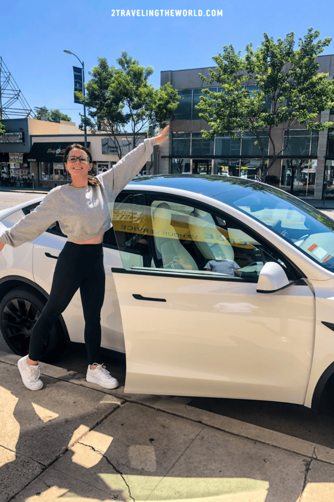 girl standing in front of her new tesla model y with hands up in the air