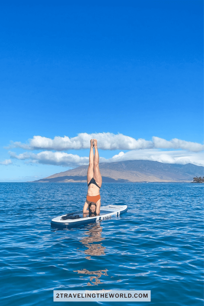 SUP paddle boarding tour in maui. woman is doing a headstand on the paddle board.