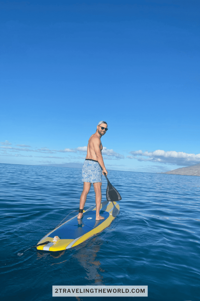 SUP paddle boarding tour in maui. Man is standing on a yellow paddle board looking back at the camera.