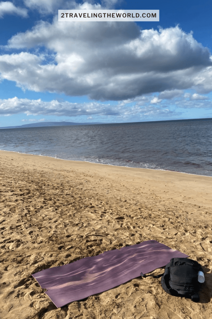 things to do in kihei is yoga on the beach maui. the image shows a purple yoga mat on the sand in kihei.