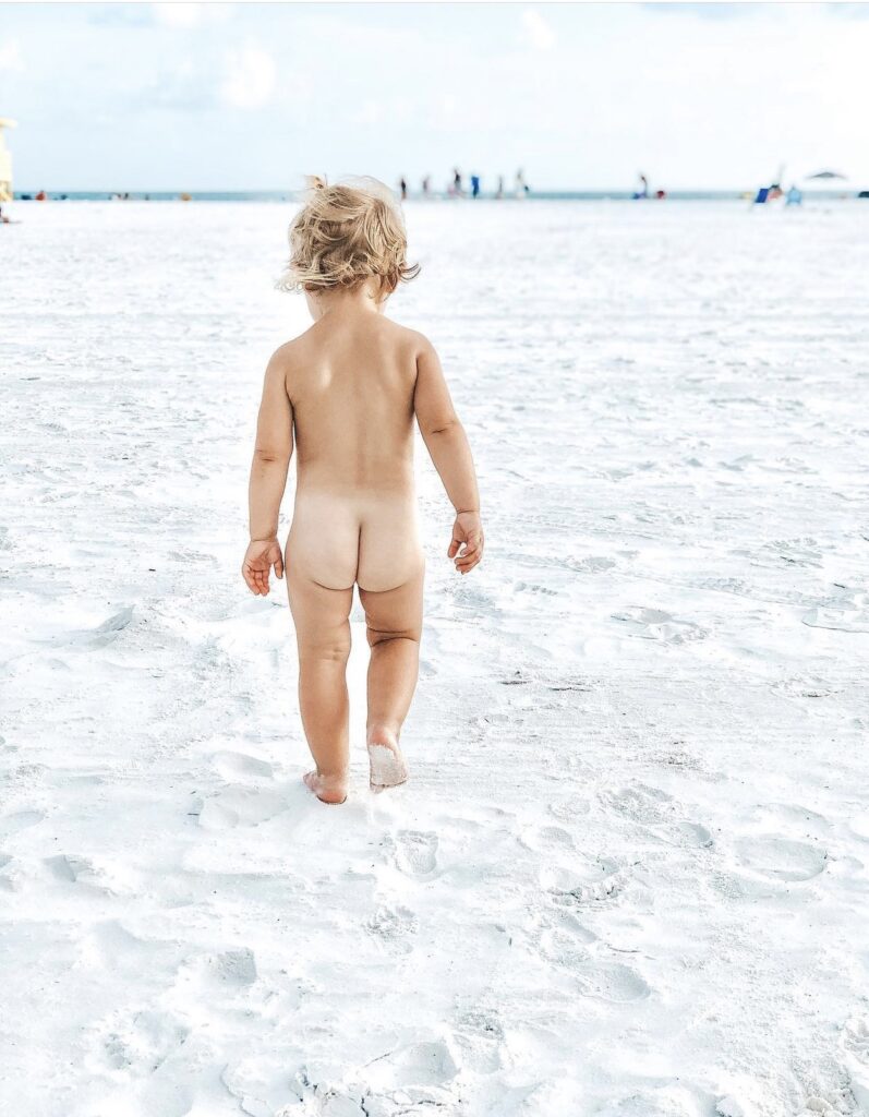 baby walking on beach wearing favorite broad spectrum sunscreen with coconut oil