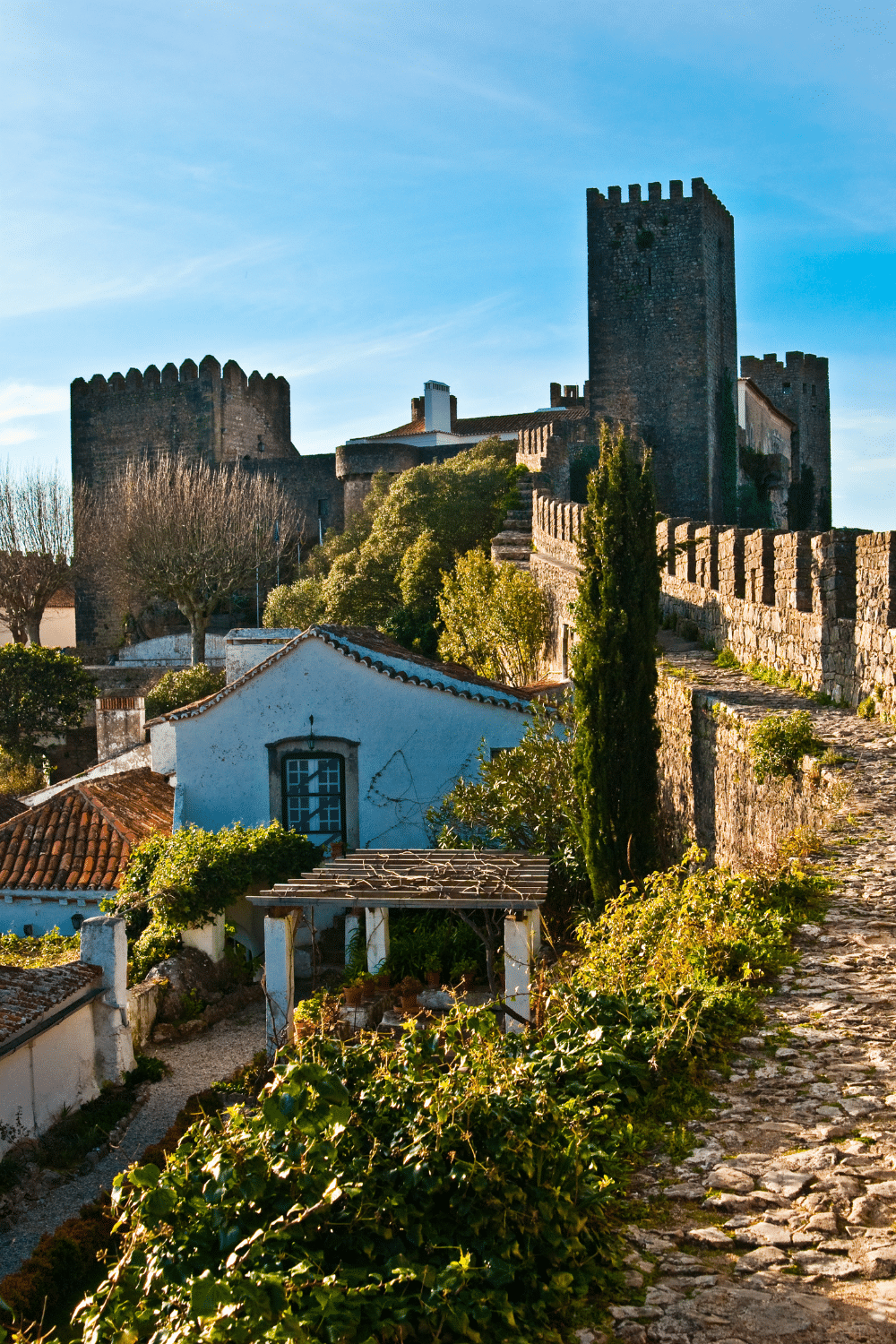 visit obidos portugal - picture shows the obidos castle walls and some of the town of obidos in portugal.