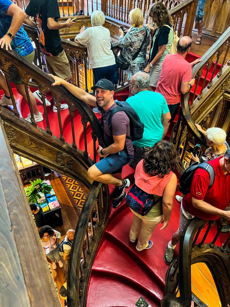 man posing on harry potter inspired book store stairs in central porto