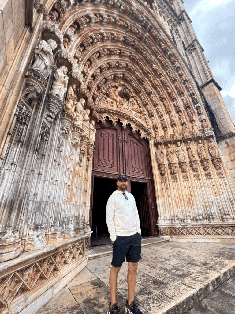 man outside of the Batalha monastery on Portugal Roadtrip. The entrance doors are incredibly fine detail