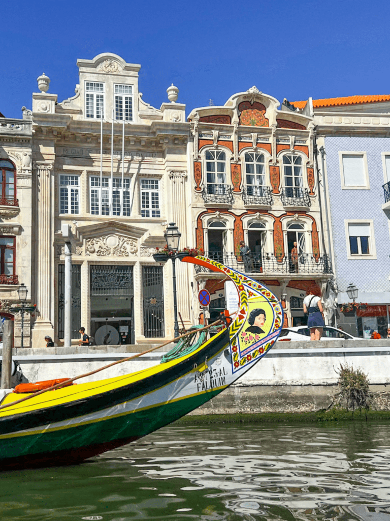 tour day to costa nova and aviero from Coimbra. boat in the water in aviero with colorful building in the background