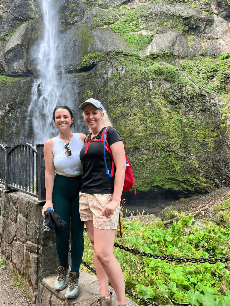 water bottles for hiking to keep water cold - two woman hiking in front of a waterfall with an ultra durable, BPA free water bottle