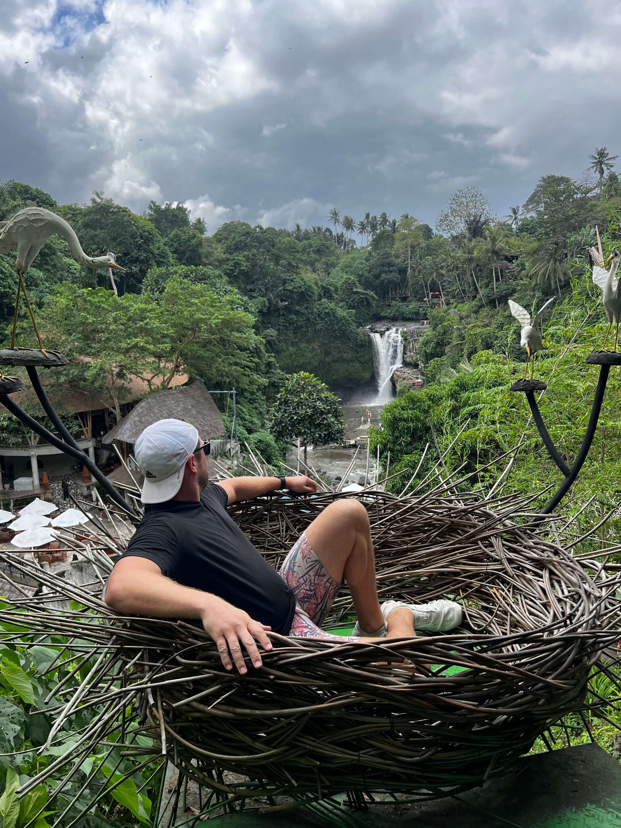 man sitting in bird nest photo opp at Tegenungan Waterfall, one of the main Tourist attractions in Bali