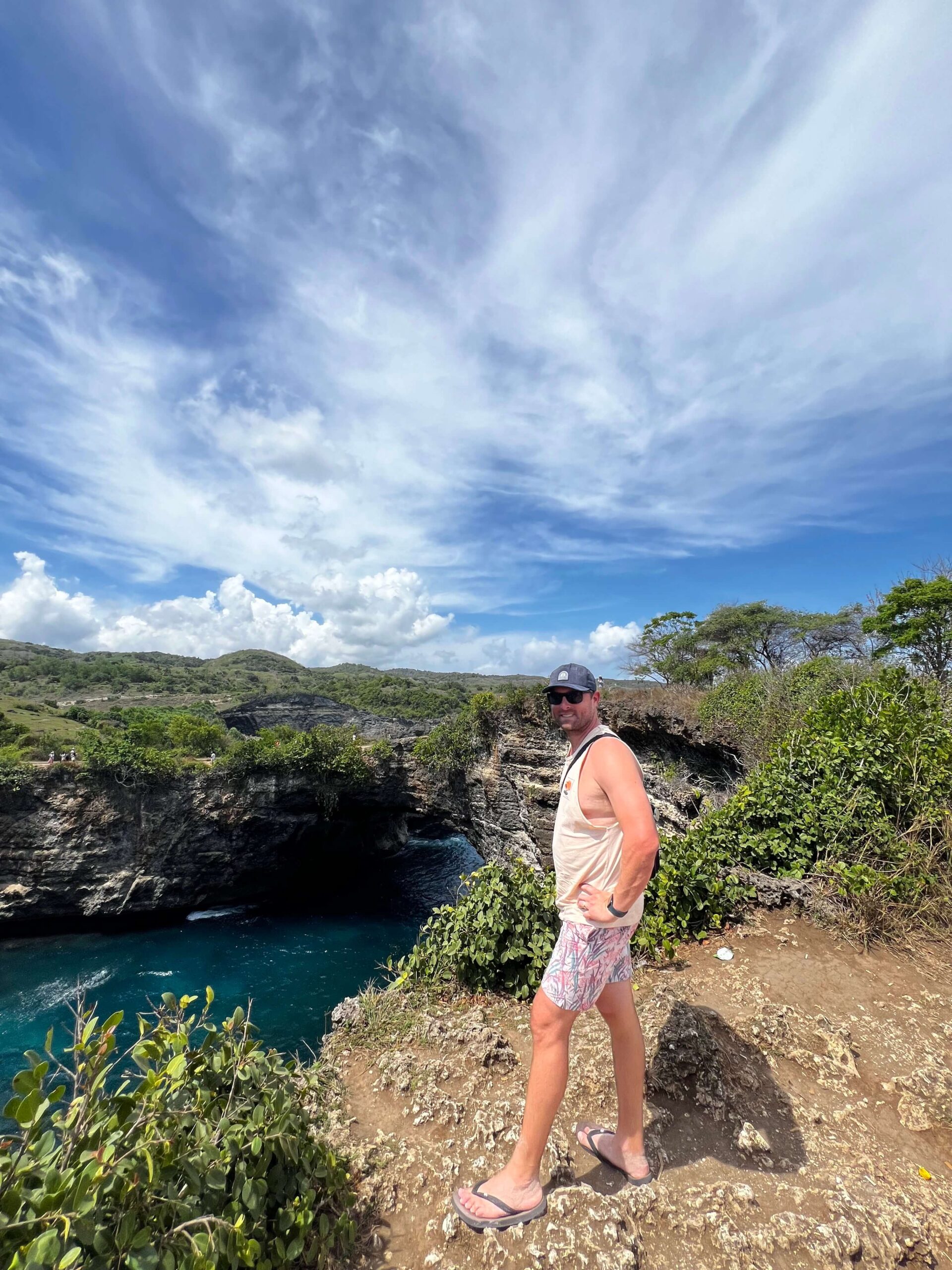 man standing at the edge overlooking the arch over Pasih Uug Beach