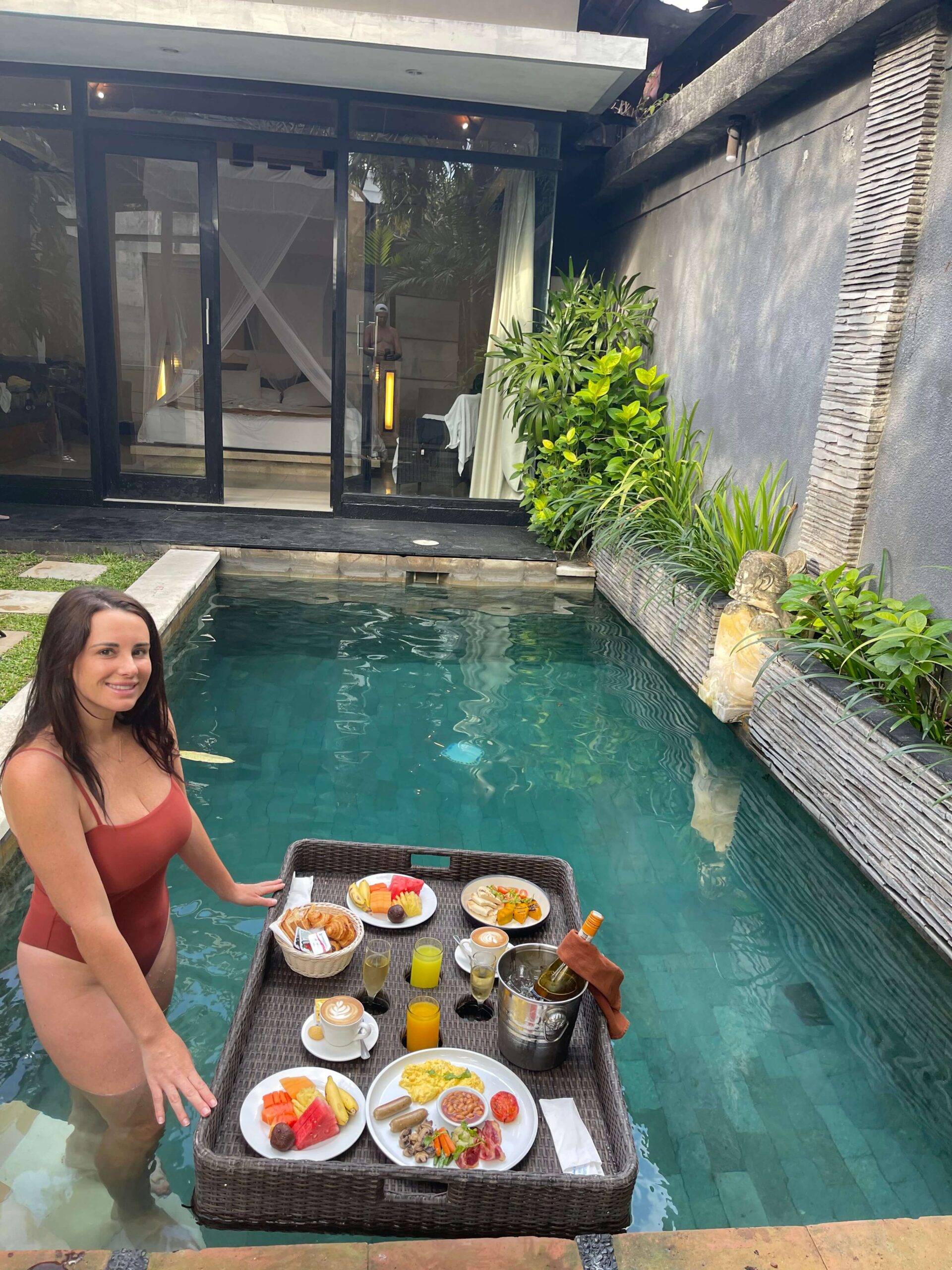 woman standing next to her floating breakfast at her Bali Vila